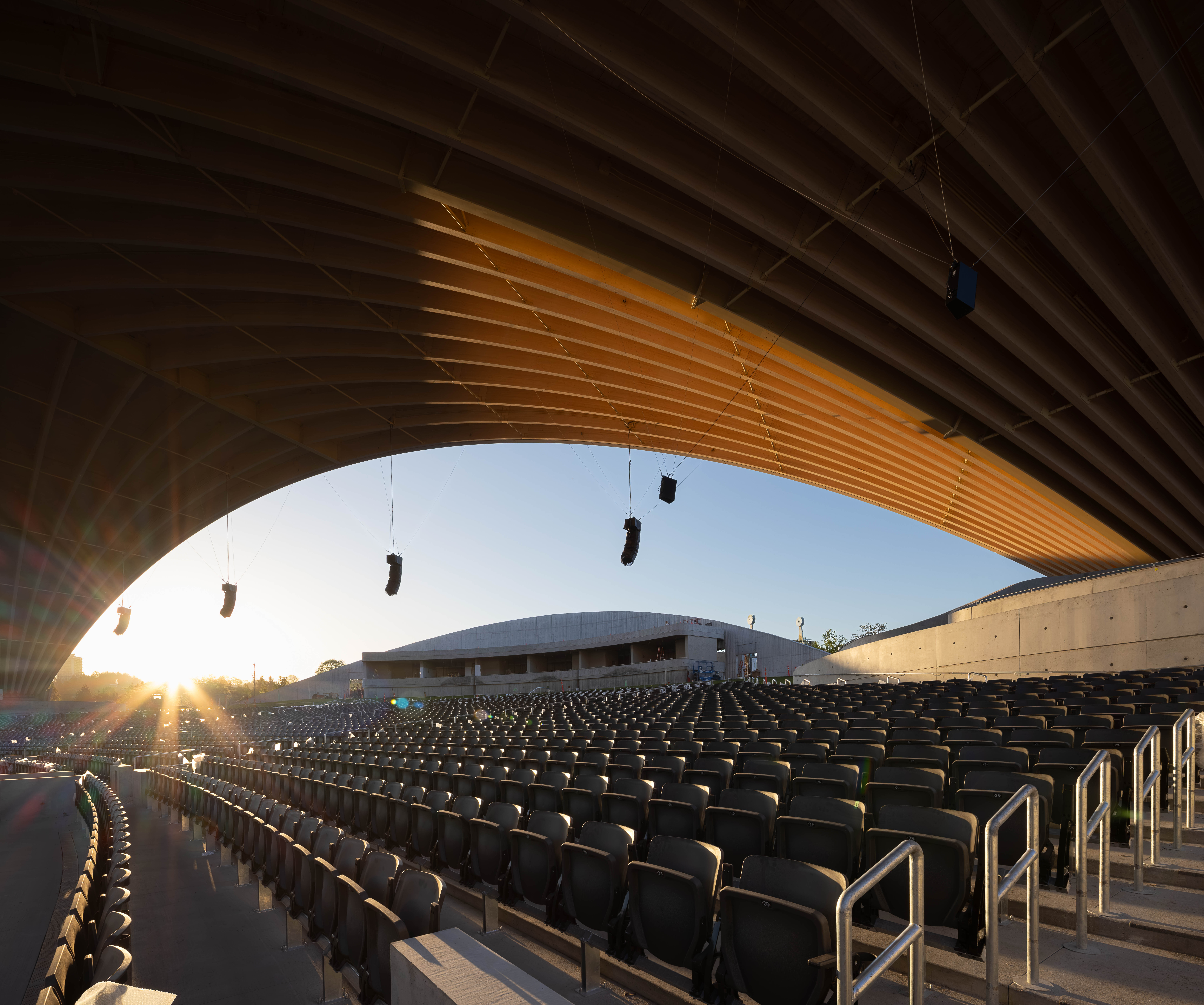 PNE Amphitheatre by Revery Architecture, Vancouver, BC - interior sunrise open air view of long-span mass timber roof